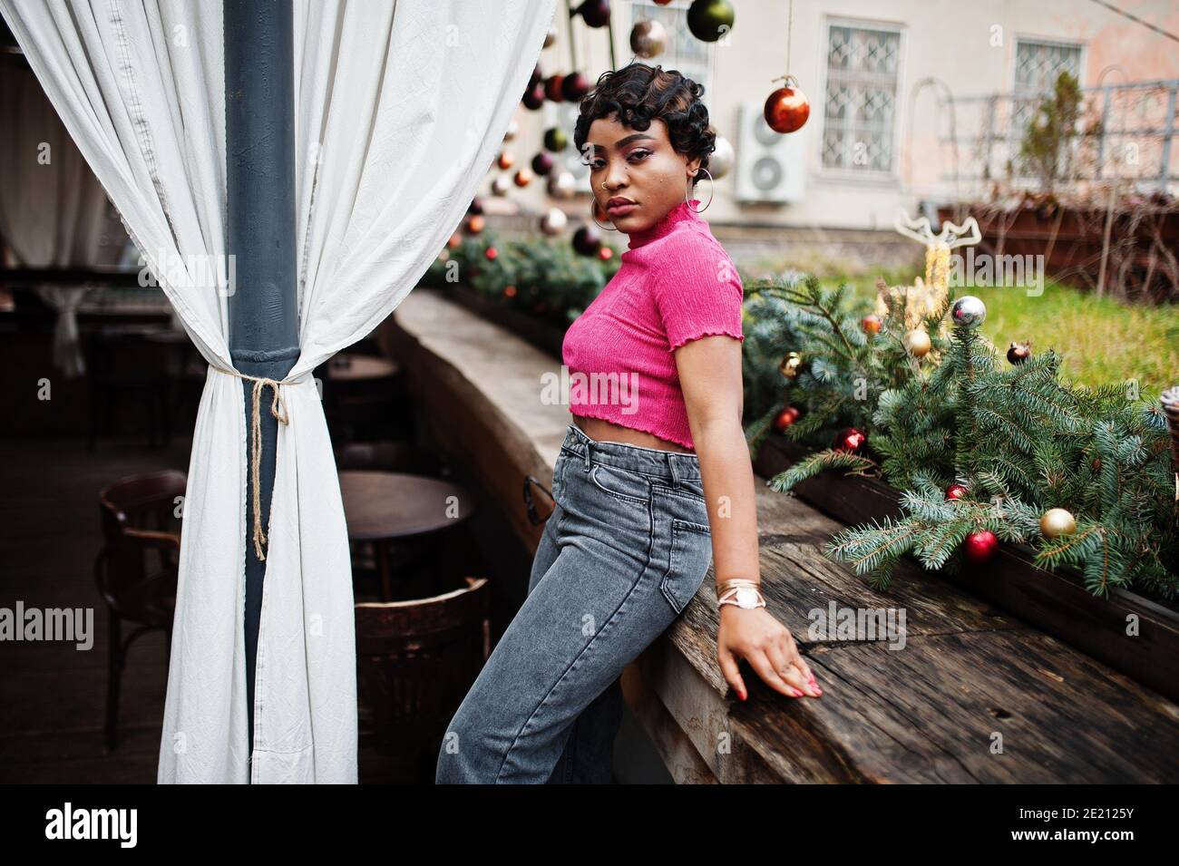Jeune femme afro-américaine urbaine en haut rose et jeans gris. Afro mode chic femmes. Banque D'Images