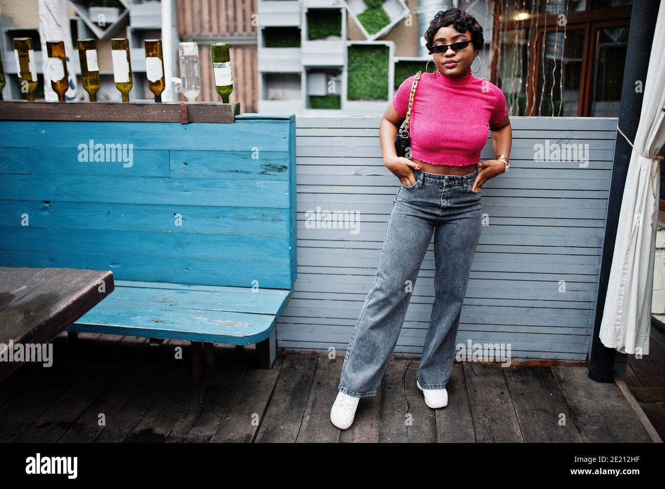 Jeune femme afro-américaine urbaine en haut rose et gris jeans et lunettes  de soleil avec sac à main. Afro mode chic femmes Photo Stock - Alamy