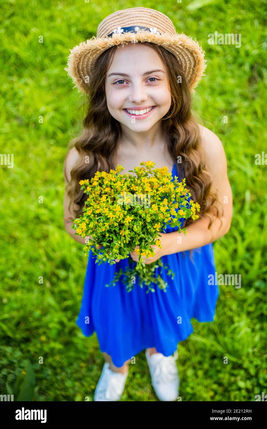 Joyeux bébé fille porter un chapeau de soleil sur les cheveux à long chemin  et la mode robe d'été tenant des fleurs paysage naturel, boutique florale  Photo Stock - Alamy