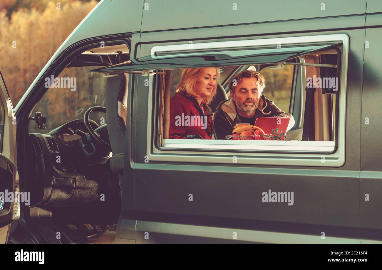 Un couple caucasien regardant un film en ligne à l'intérieur de leur fourgonnette moderne pendant leur week-end de escapade. Véhicule récréatif RV et Camping thème. Banque D'Images