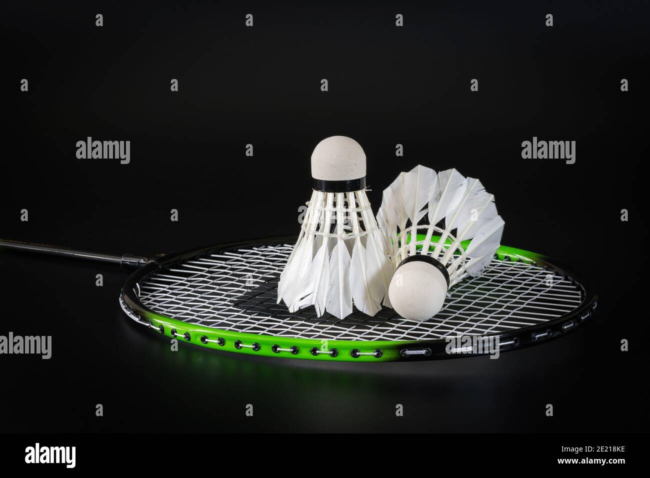 Le ballon de badminton est placé sur le filet de la raquette de badminton sur fond noir. Sports et loisirs. Banque D'Images