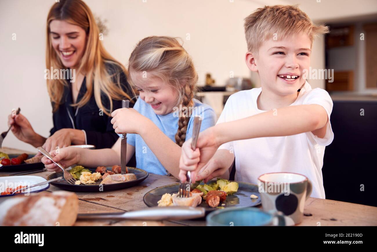 Famille assis autour de la table à la maison dans un pyjama en appréciant le brunch Ensemble Banque D'Images