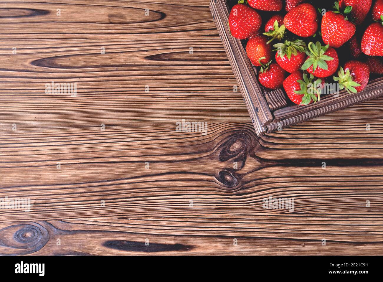 Fraises dans une boîte en bois sur un fond naturel en bois naturel, flou comme une technique artistique de l'auteur espace de copie de gros plan Banque D'Images