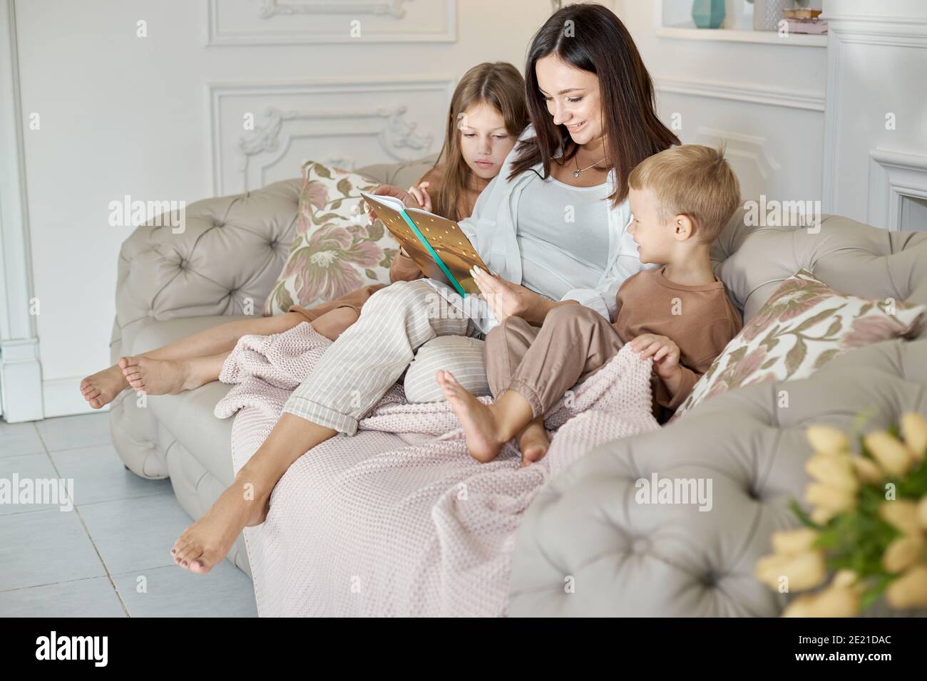 Maman lit un livre aux enfants. Une femme raconte une histoire à un garçon  et une fille avant d'aller au lit. Maman, fille et fils se détendent à la  maison lors d'une