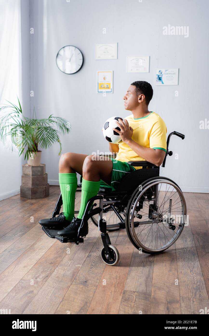 sportif afro-américain handicapé en fauteuil roulant tenant un ballon de football Banque D'Images sportif afro-américain handicapé en fauteuil roulant tenant un ballon de football Banque D'Images