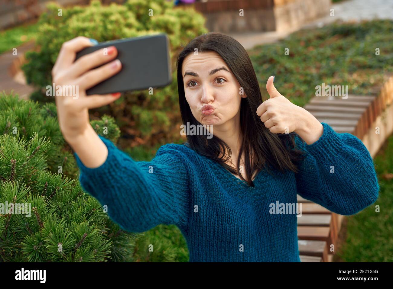 Une jolie étudiante envoie un baiser et montre le pouce pendant faire une  photo delle-même à lextérieur dune façade verte confortable Photo Stock  - Alamy