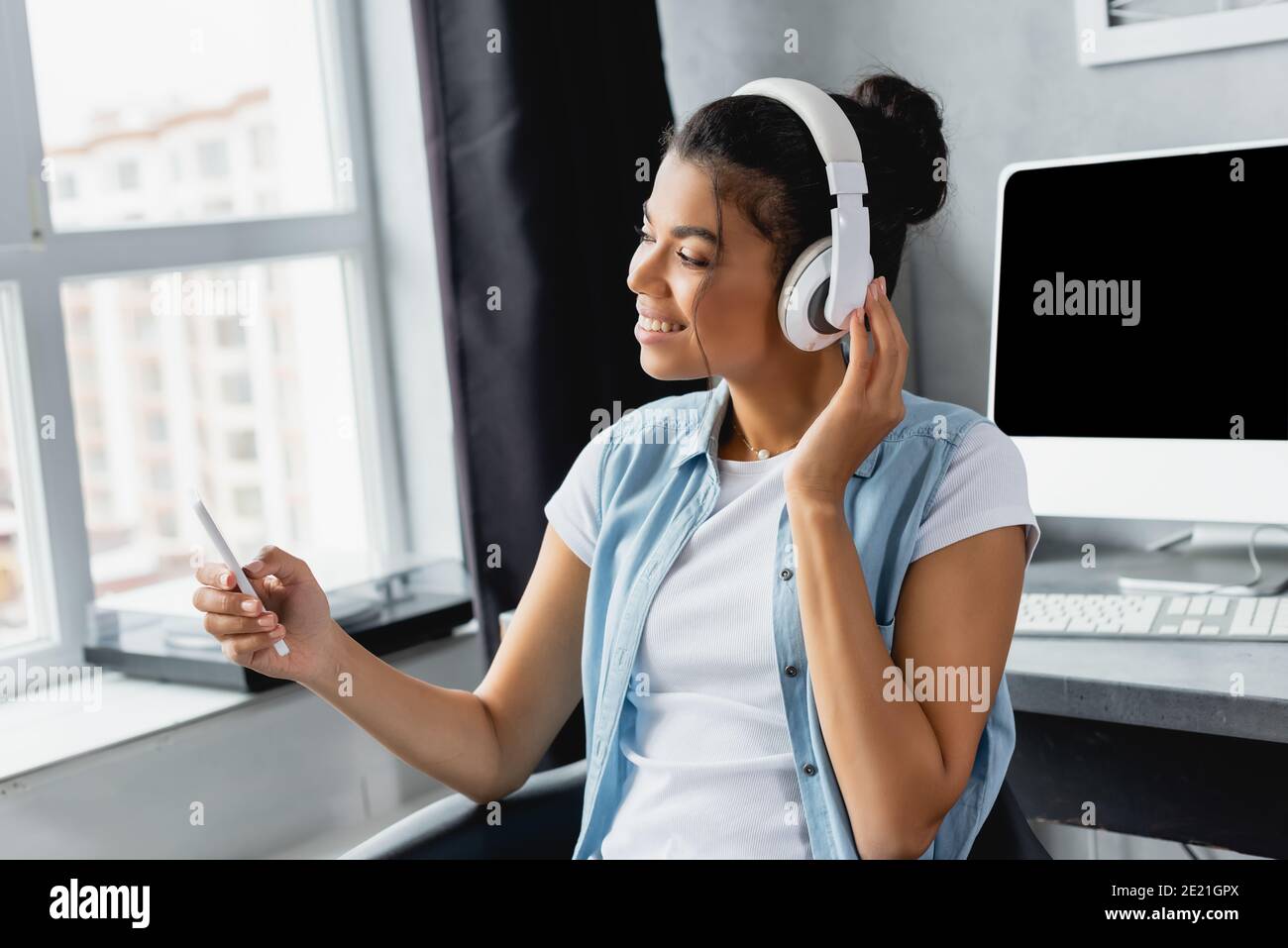 messages de freelance afro-américains sur smartphone tout en écoutant de la musique dans un casque sans fil à la maison Banque D'Images