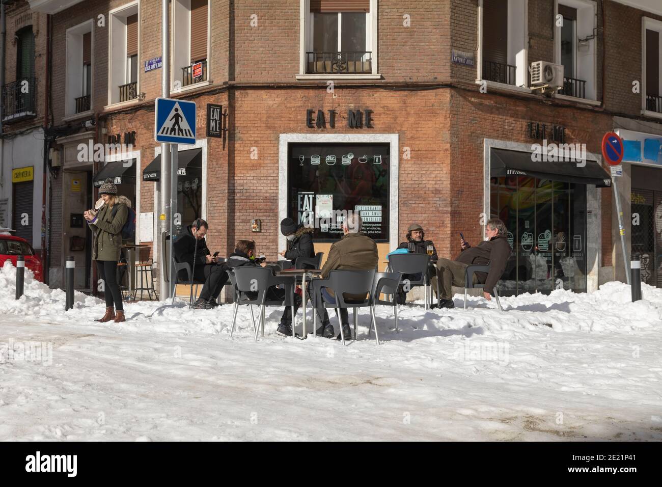 Madrid, Espagne - 10 janvier 2021 : un groupe de personnes profitent du soleil et d'une bière dans un bar ouvert, dans le quartier de Retiro, après la tempête, par une journée enneigée. Banque D'Images