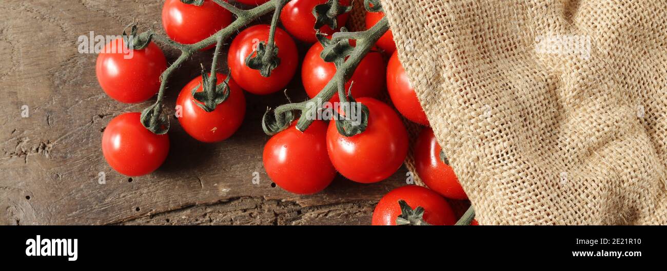 Fond rustique avec tomates, sac en toile sur fond en bois ancien. Cuisine rustique avec tomates Banque D'Images