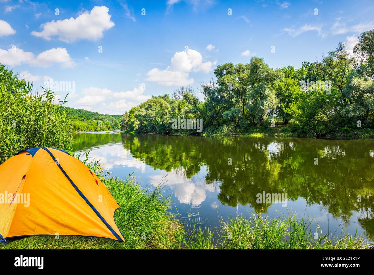 Tente touristique jaune près de la rivière forestière en été Banque D'Images