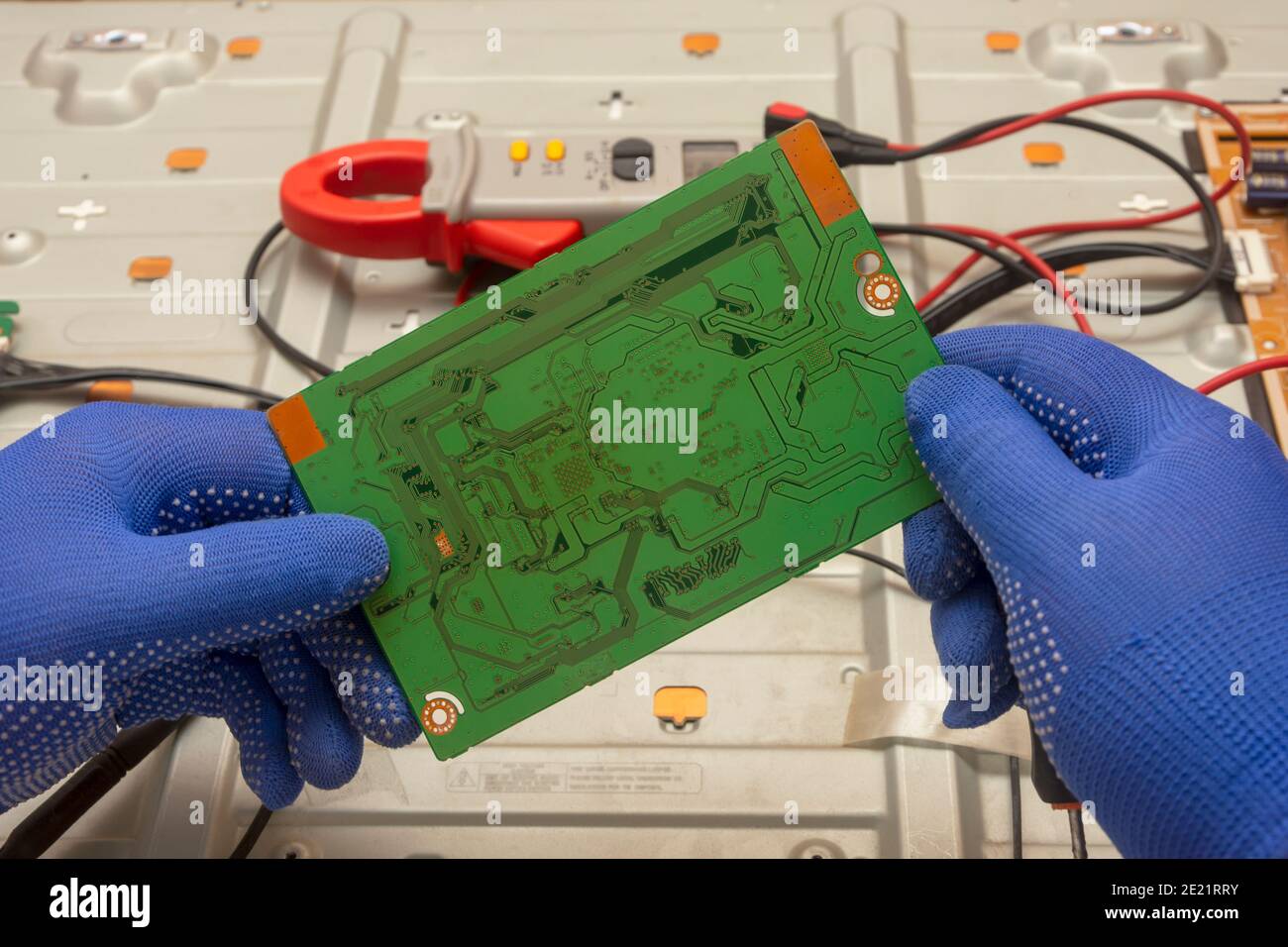 Circuit imprimé vert du téléviseur LCD entre les mains d'un électricien. Gros plan, mise au point sélective. Banque D'Images