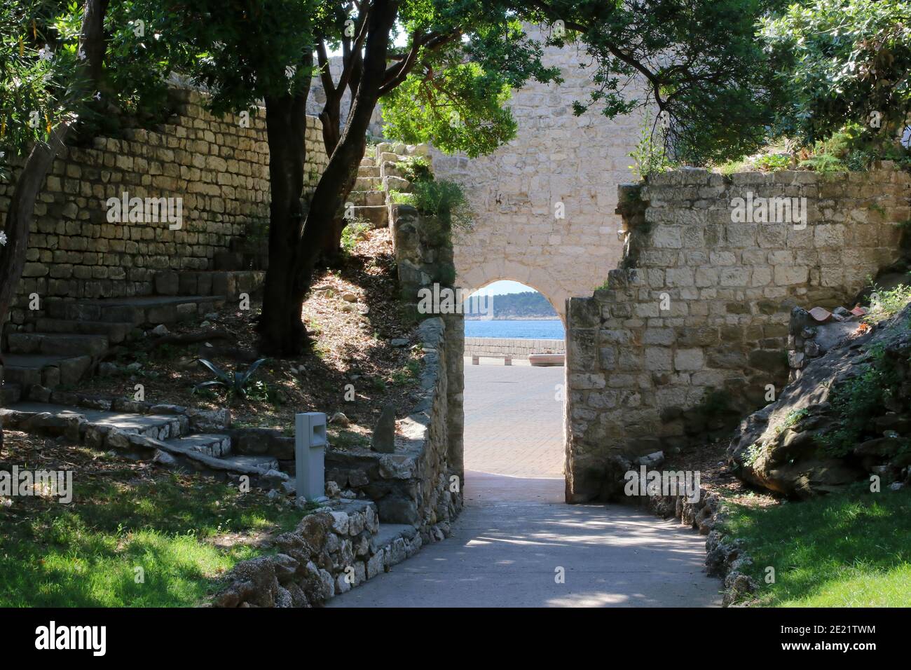 Porte dans un ancien mur en pierre, donnant sur l'eau azur de la ville de Rab, Croatie Banque D'Images