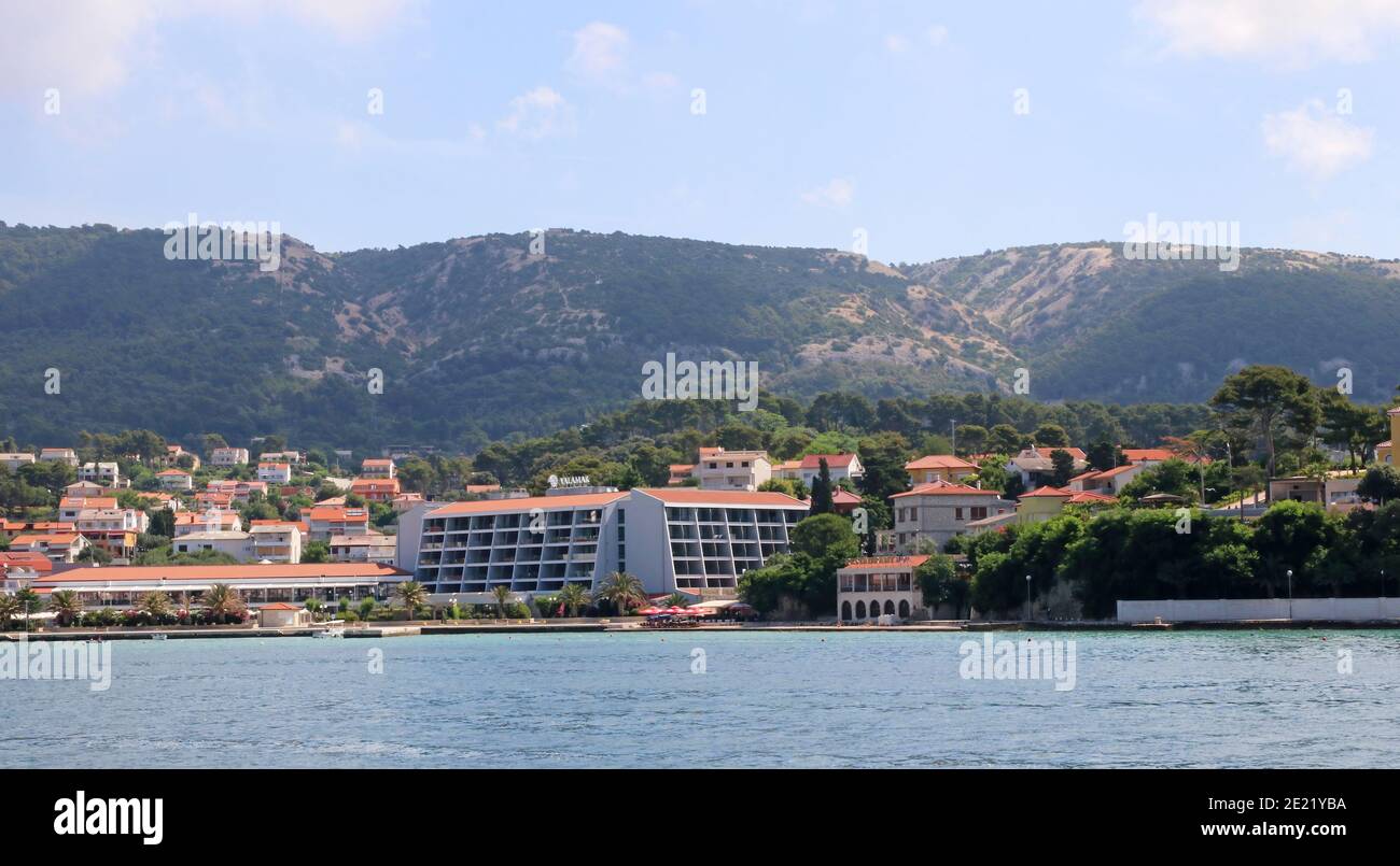 Croatie, région de Kvarner, Rab Island Hôtel moderne sur le front de mer avec des collines derrière elle. Banque D'Images