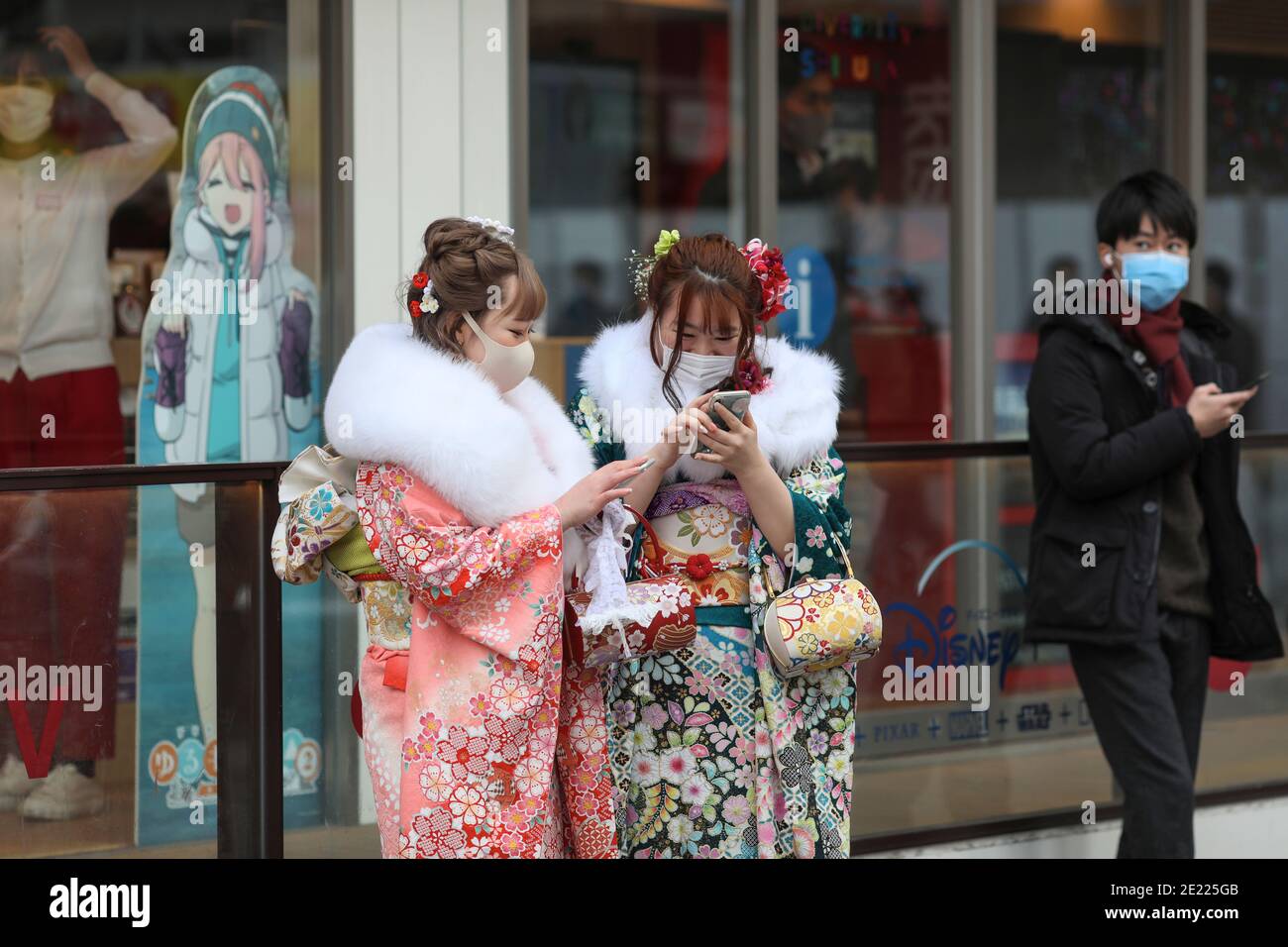 Les femmes portant des kimono et des masques qui passent du temps à Shibuya Crossing pendant la journée « Coming of Age » en Tokyo.Coming de la Journée de l'âge célèbre ceux qui ont atteint l'âge de 20 ans. C'est un jour férié le deuxième lundi de janvier au Japon. Cependant, à la lumière du taux croissant d'infection par COVID19 au Japon, le jour de l'âge de 2021 n'était pas le même comme d'habitude. La cérémonie officielle n'était en ligne que dans la plupart des bureaux de la ville au Japon. Dans la place populaire Shibuya Crossing n'était que peu de filles dans le magnifique kimono. Toutes les personnes portant un masque. Banque D'Images
