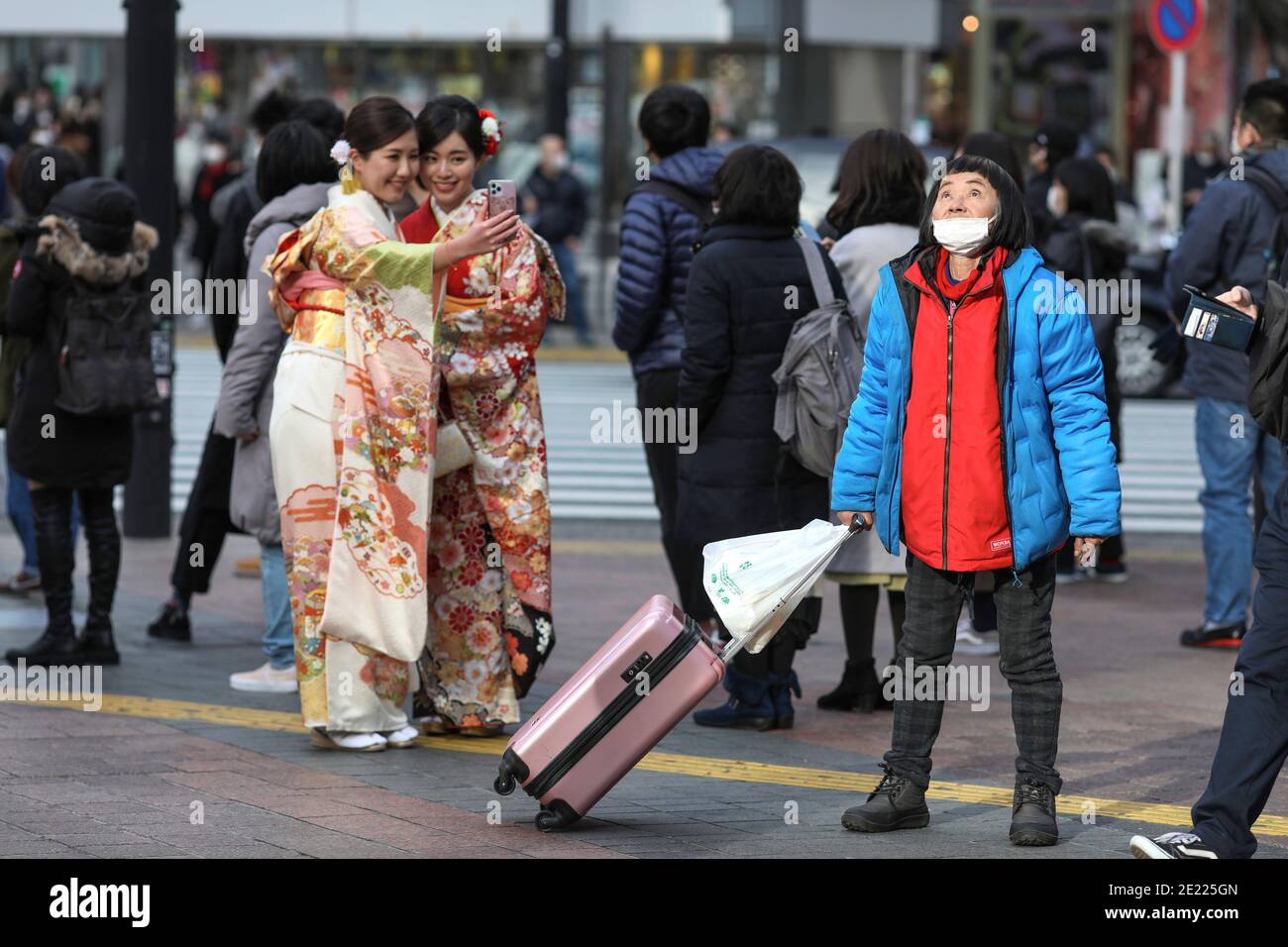 Les femmes vêtues de kimono prennent des photos à Shibuya Crossing pendant le jour de 'Coming of Age' en Tokyo.Coming du jour de l'âge célèbre ceux qui ont 20 ans. C'est un jour férié le deuxième lundi de janvier au Japon. Cependant, à la lumière du taux croissant d'infection par COVID19 au Japon, le jour de l'âge de 2021 n'était pas le même comme d'habitude. La cérémonie officielle n'était en ligne que dans la plupart des bureaux de la ville au Japon. Dans la place populaire Shibuya Crossing n'était que peu de filles dans le magnifique kimono. Toutes les personnes portant un masque. Banque D'Images