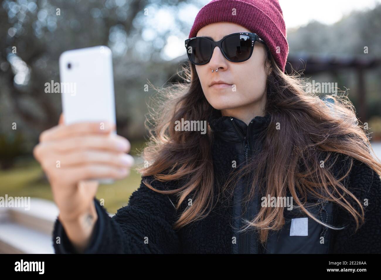 Femme portant un bonnet rouge et des lunettes de soleil prenant un selfie à  l'extérieur Photo Stock - Alamy