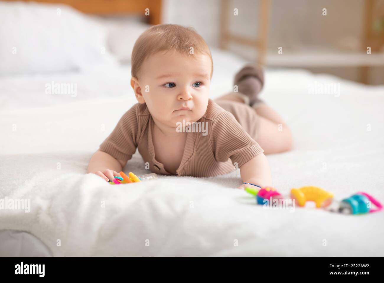 Mignon petit bébé jouant avec des jouets sur le lit Banque D'Images