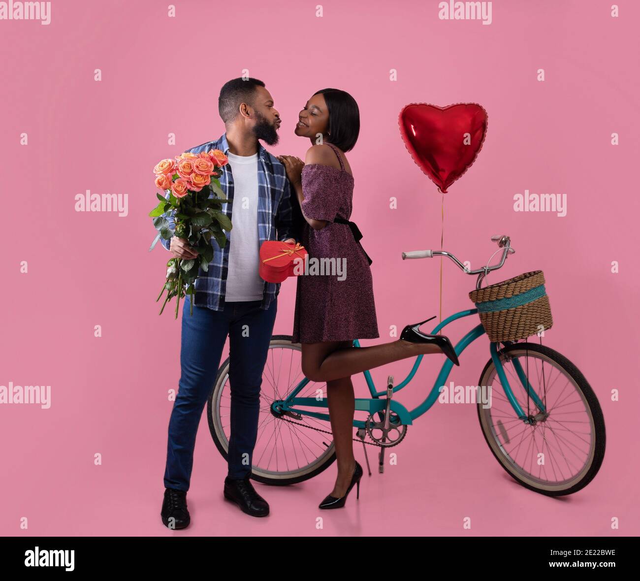 Portrait complet de beau couple noir avec roses, cadeau de la Saint-Valentin  et baiser de vélo sur fond rose studio Photo Stock - Alamy