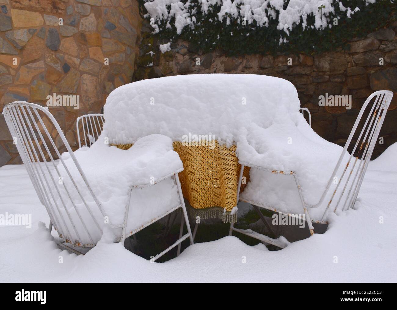 Table avec nappe orange-jaune et deux chaises recouvertes de neige. Scène de jardin après le passage de la tempête Filomena à travers l'Espagne. Janvier 2021. Banque D'Images