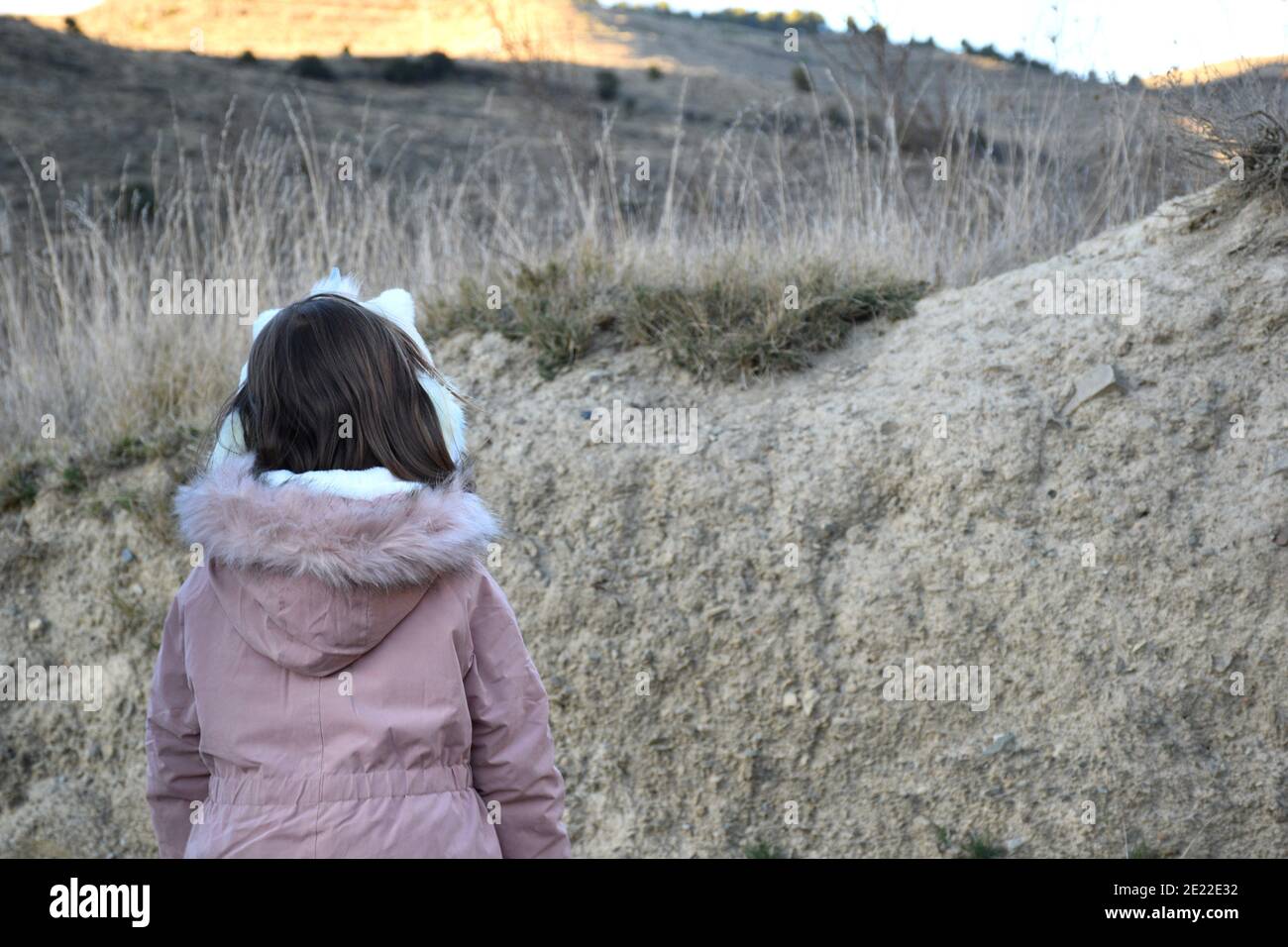 Jeune fille de cinq ans avec une veste rose et un bandeau unicorn sur le dos. À côté d'un remblai dans une zone de champ. Banque D'Images