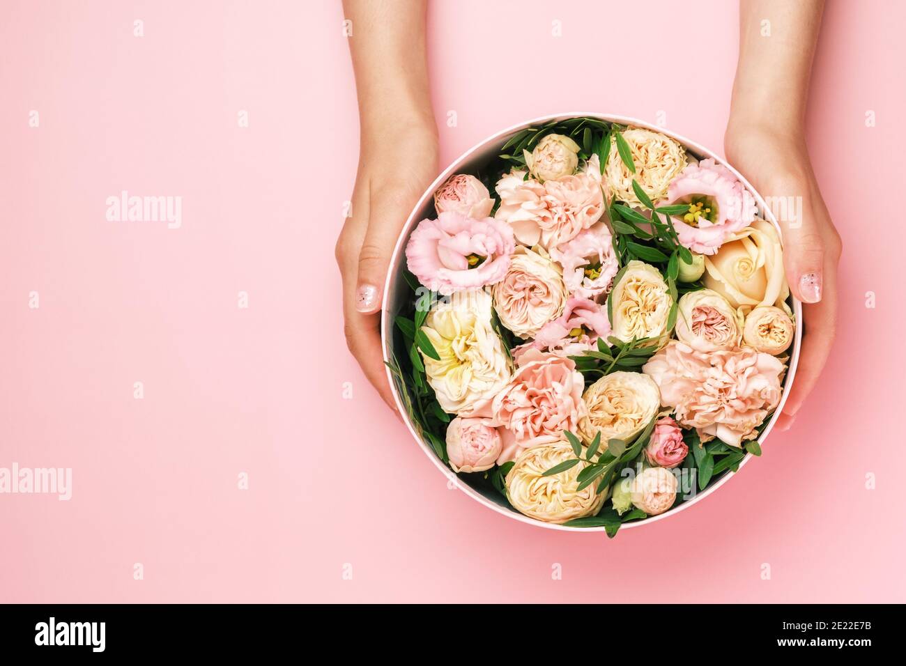 Fleuriste tenant un chapeau boîte ronde avec composition florale sur fond  rose avec espace de copie. Boîte cadeau pour le 8 mars, Saint-Valentin,  Fête des mères Photo Stock - Alamy