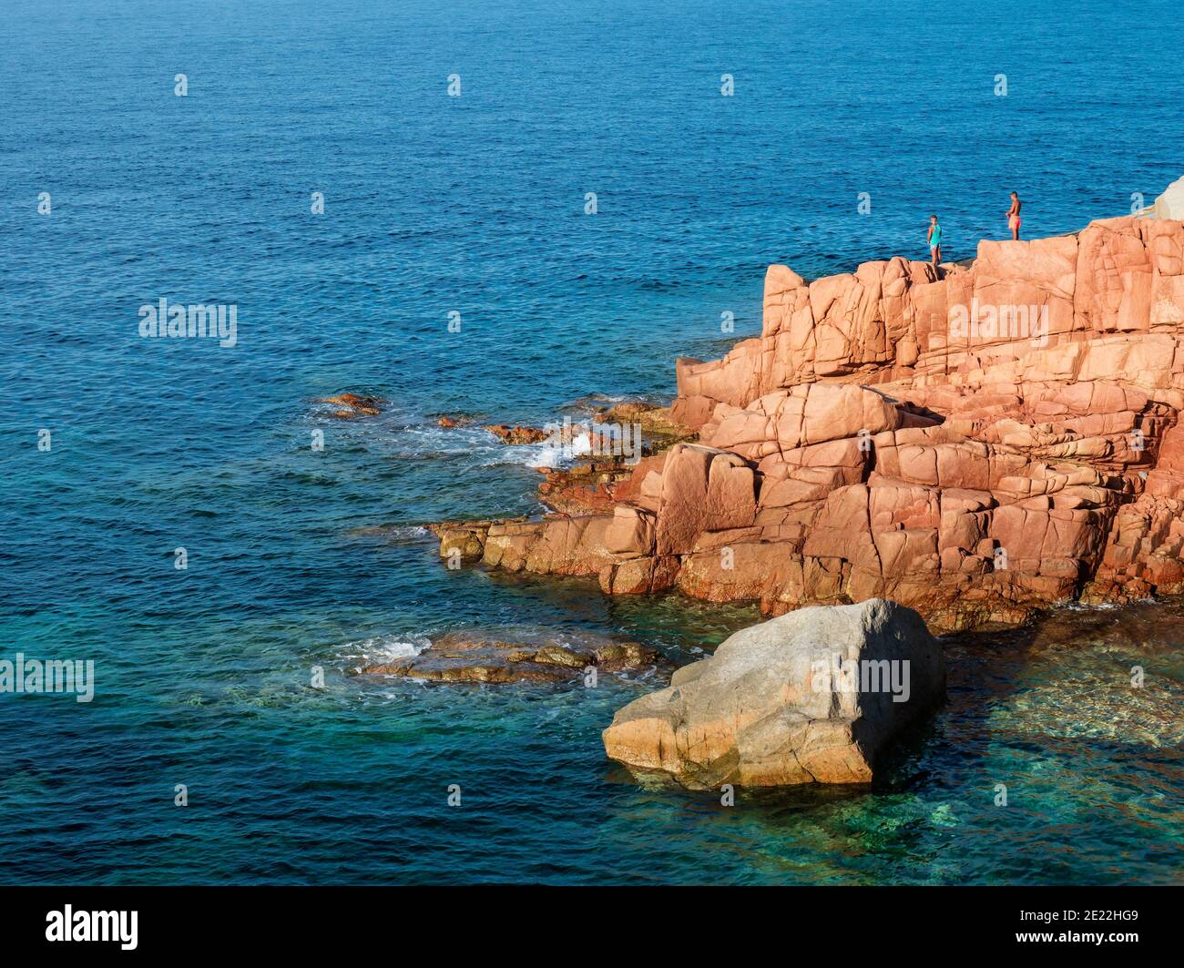 Red Rocks appelé Rocce Rosse au bord de la mer méditerranée à Arbatax avec deux garçons pêchant. Tortoli, Ogliastra, Sardaigne, Italie. Jour ensoleillé d'été Banque D'Images