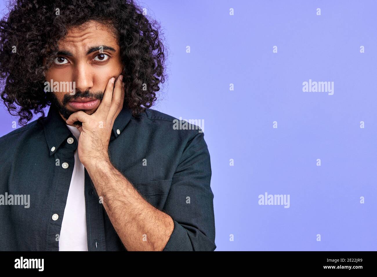 homme arabe mélancolique regarde l'appareil photo avec tristesse, jeune homme dans une chemise décontractée est bouleversé par les nouvelles. isolé sur fond violet Banque D'Images