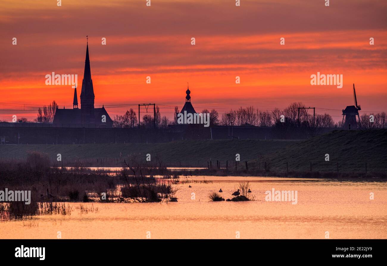 Tour de cloche, tour de porte et moulin à vent de la ville Culemborg silhouetted contre le lever du soleil en hiver, Gelderland, pays-Bas Banque D'Images