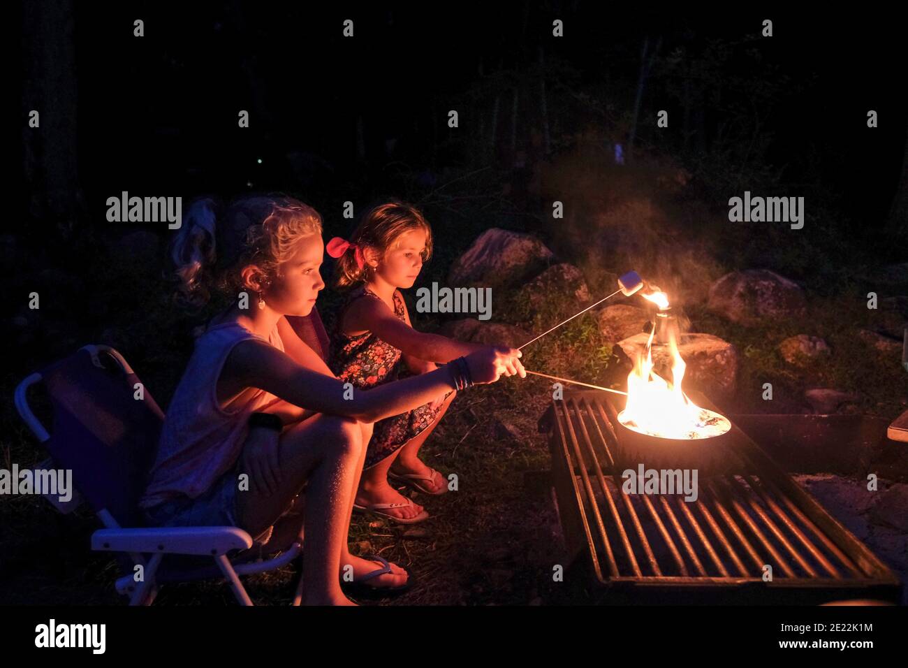 deux filles rôtisant des guimauves sur feu ouvert, campant en été Banque D'Images