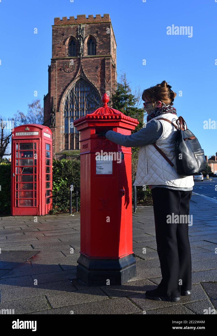 Une femme posta une lettre dans une boîte postale victorienne de forme hexagonale à Shrewsbury, au Royaume-Uni. L'un des 50 seuls a fait qu'ils ont été conçus par I.W. Penfold et fabriqué par C Banque D'Images