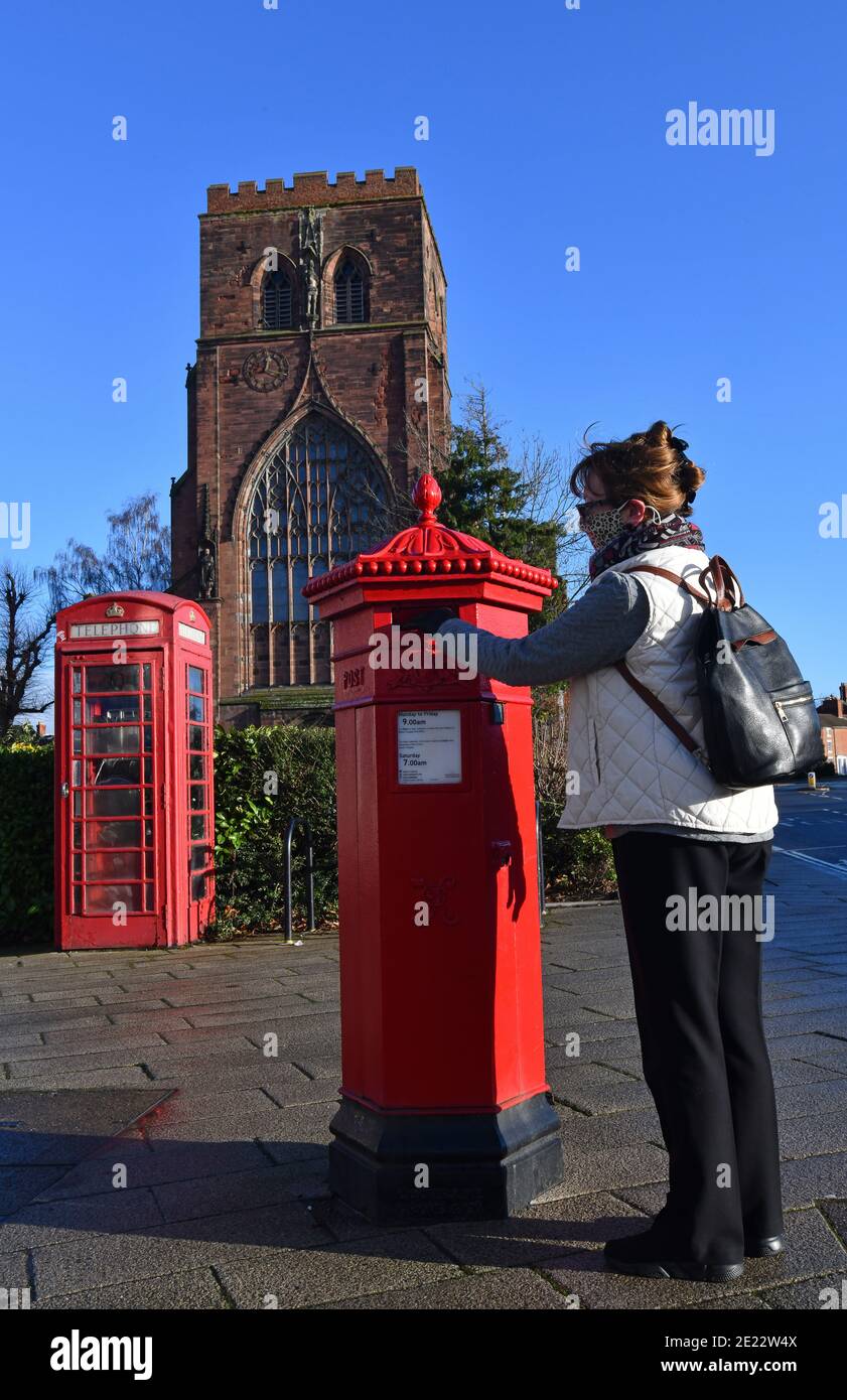 Une femme posta une lettre dans une boîte postale victorienne de forme hexagonale à Shrewsbury, au Royaume-Uni. L'un des 50 seuls a fait qu'ils ont été conçus par I.W. Penfold et fabriqué par C Banque D'Images