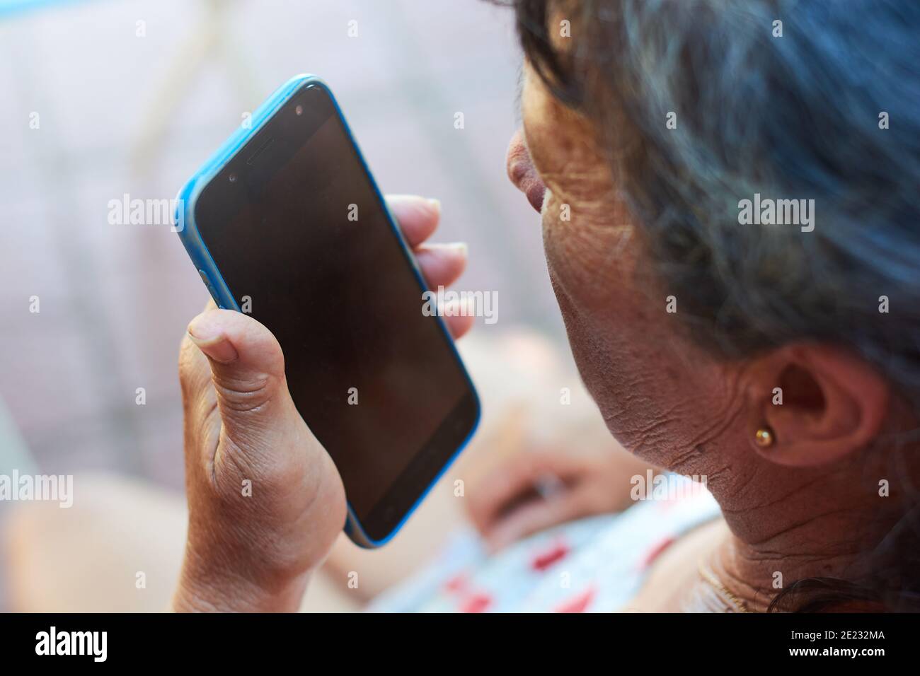 Femme brune adulte vêtue de vêtements décontractés parlant au téléphone pendant qu'elle se repose à la maison. Femme de ménage appréciant son temps libre. Arrière-plan flou. Banque D'Images