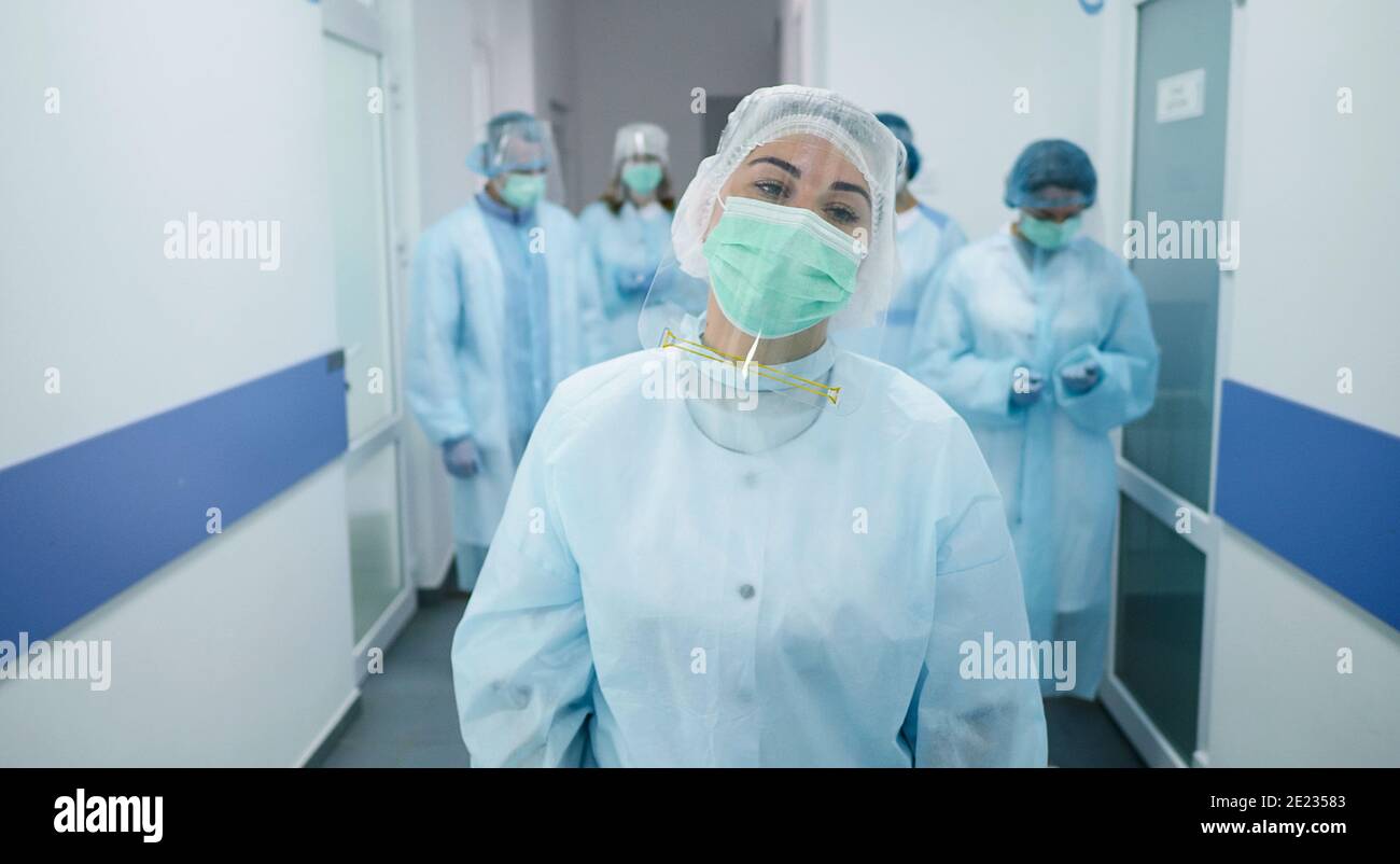 Équipe de médecins en costumes de protection. Les travailleurs médicaux masqués marchent le long du couloir d'un hôpital moderne. Combattre Covid-2019. Médecins de la clinique Banque D'Images