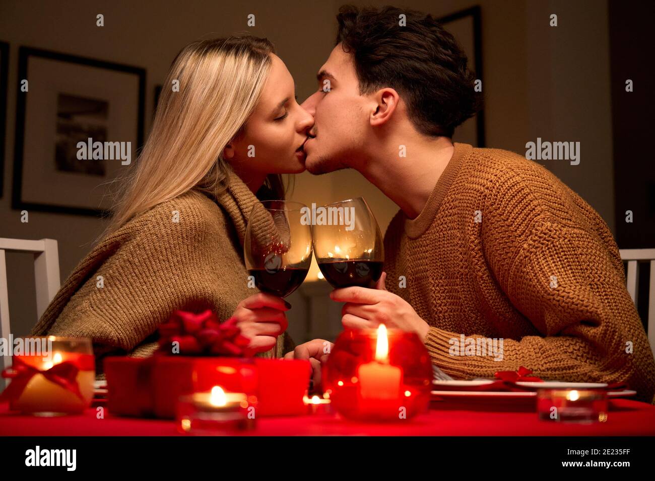 Couple heureux amoureux embrassant lors d'un dîner romantique à la maison célébrant l'anniversaire. Banque D'Images