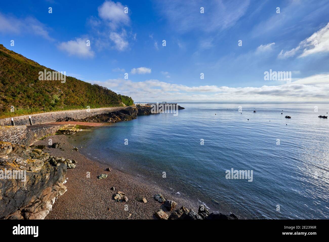 Image de Bouley Bay, un matin ensoleillé avec ciel bleu avec un peu de nuages, plage de galets, mer douce et port en arrière-plan. Îles Jersey Channel Banque D'Images