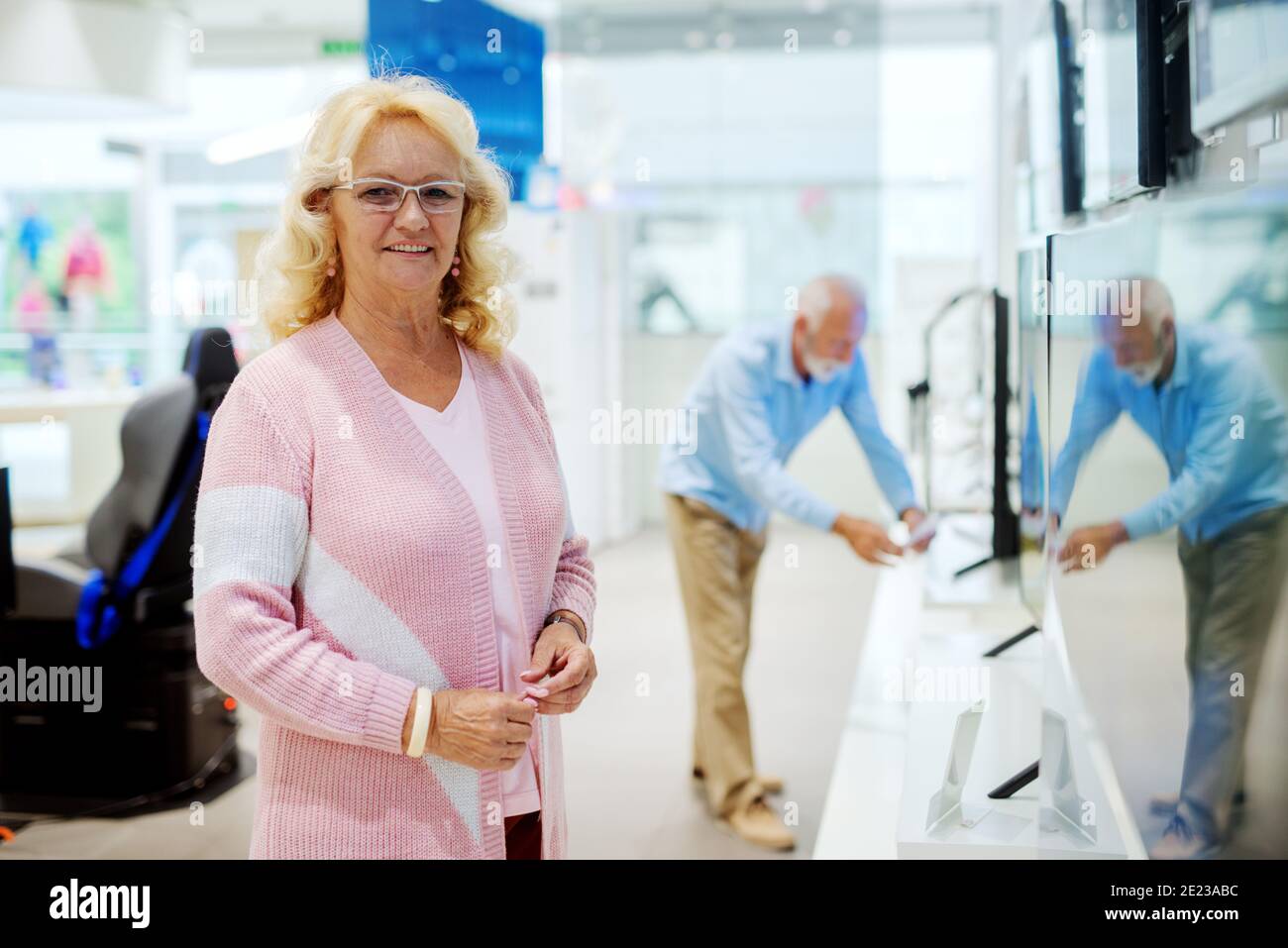 Magnifique portrait de femme âgée dans un magasin de technologie. À la recherche d'un nouveau téléviseur Smart TV. Banque D'Images