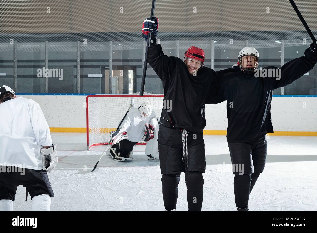 Deux joueurs de hockey excités en uniforme sportif, gants et casques de protection debout devant la caméra après le jeu et exprimant la joie Banque D'Images
