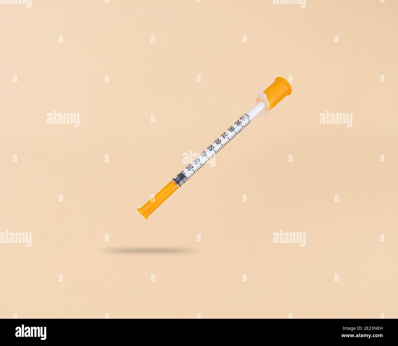 Seringue d'insuline de lévitation sur fond beige avec ombre sous elle. Banque D'Images