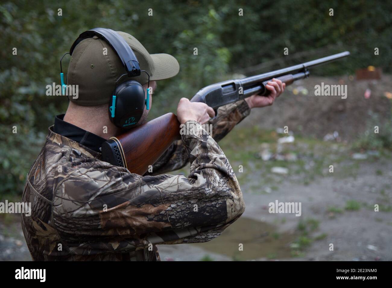 Un homme vêtu de camouflage vise un vieux fusil de chasse en bois prêt à tirer la gâchette. Banque D'Images