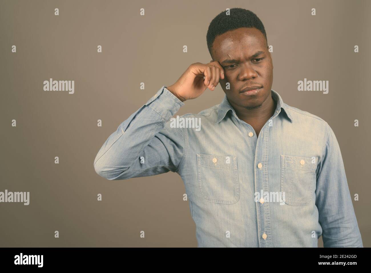 Young African man wearing denim shirt contre l'arrière-plan gris Banque D'Images