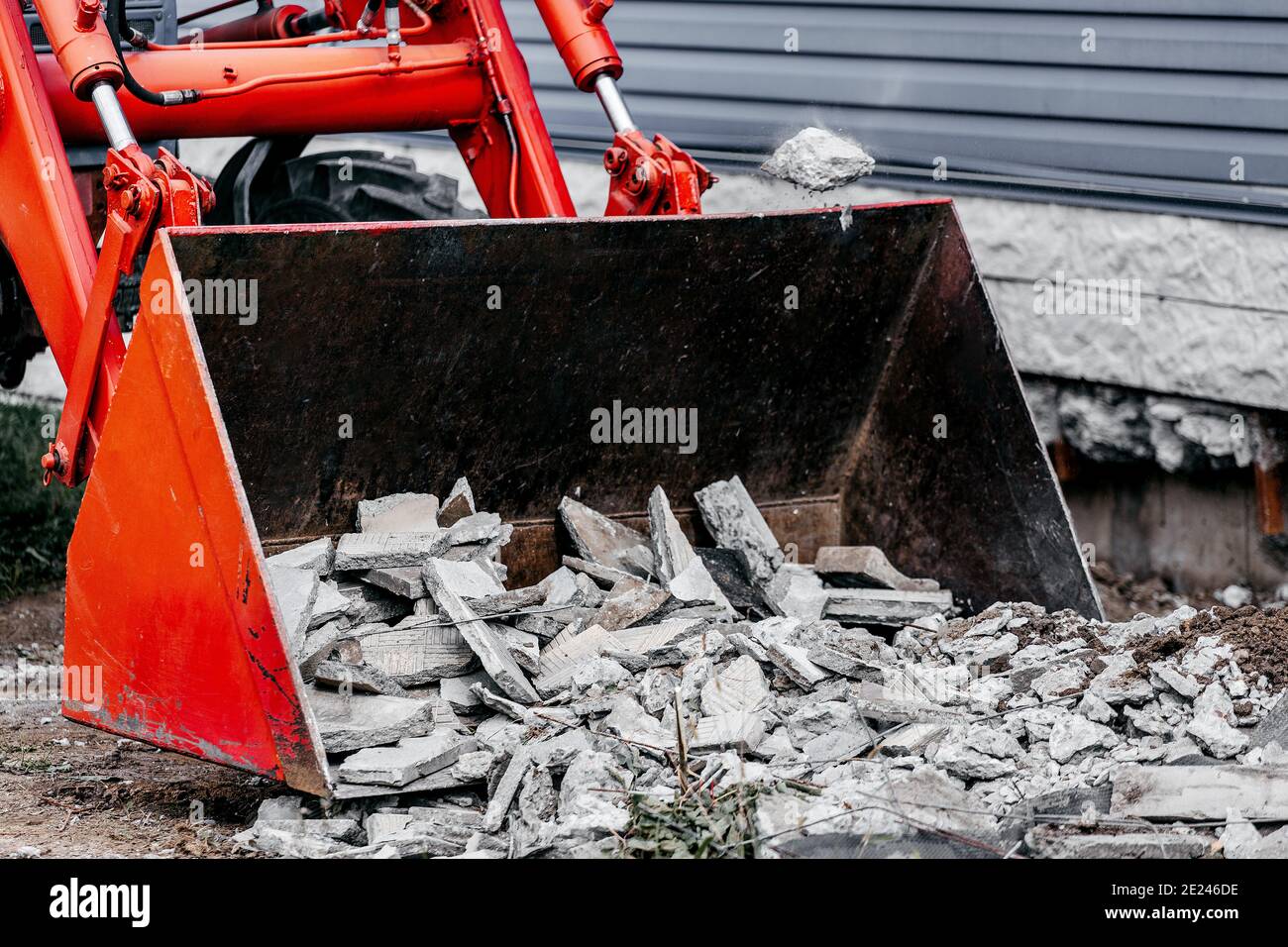 Élimination des débris de construction. Le godet du tracteur est rempli de débris de béton et de pavés. Banque D'Images