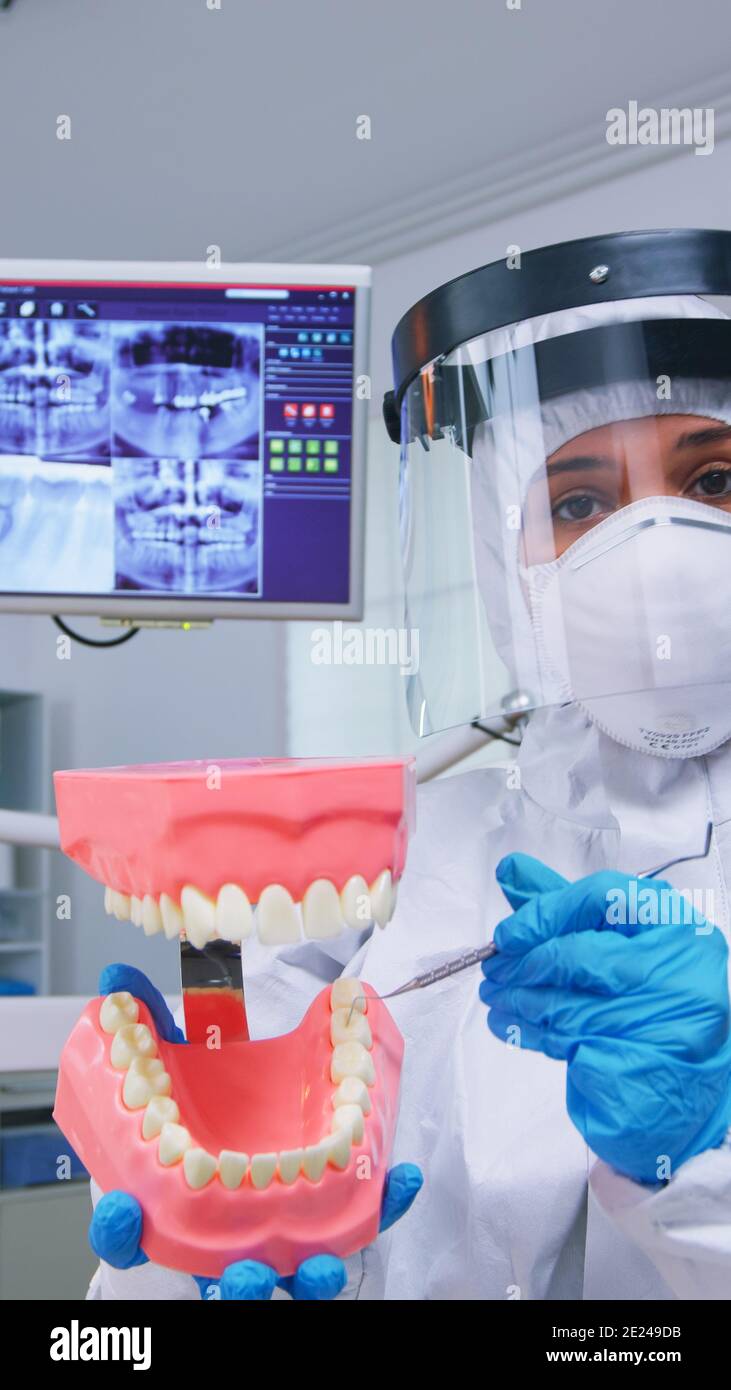 Patient pov du dentiste montrant la bonne façon de nettoyer les dents  porter la précaution contre le covid dans le cabinet dentaire en utilisant  l'accessoire squelette. Stomatolog portant un équipement de sécurité