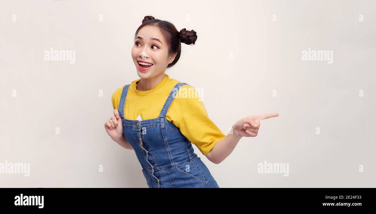 Portrait d'asiatique belle jeune femme pointant d'une main avec le doigt sur le côté supérieur gauche avec le visage de sourire. Concept de publicité et de présentation. Banque D'Images