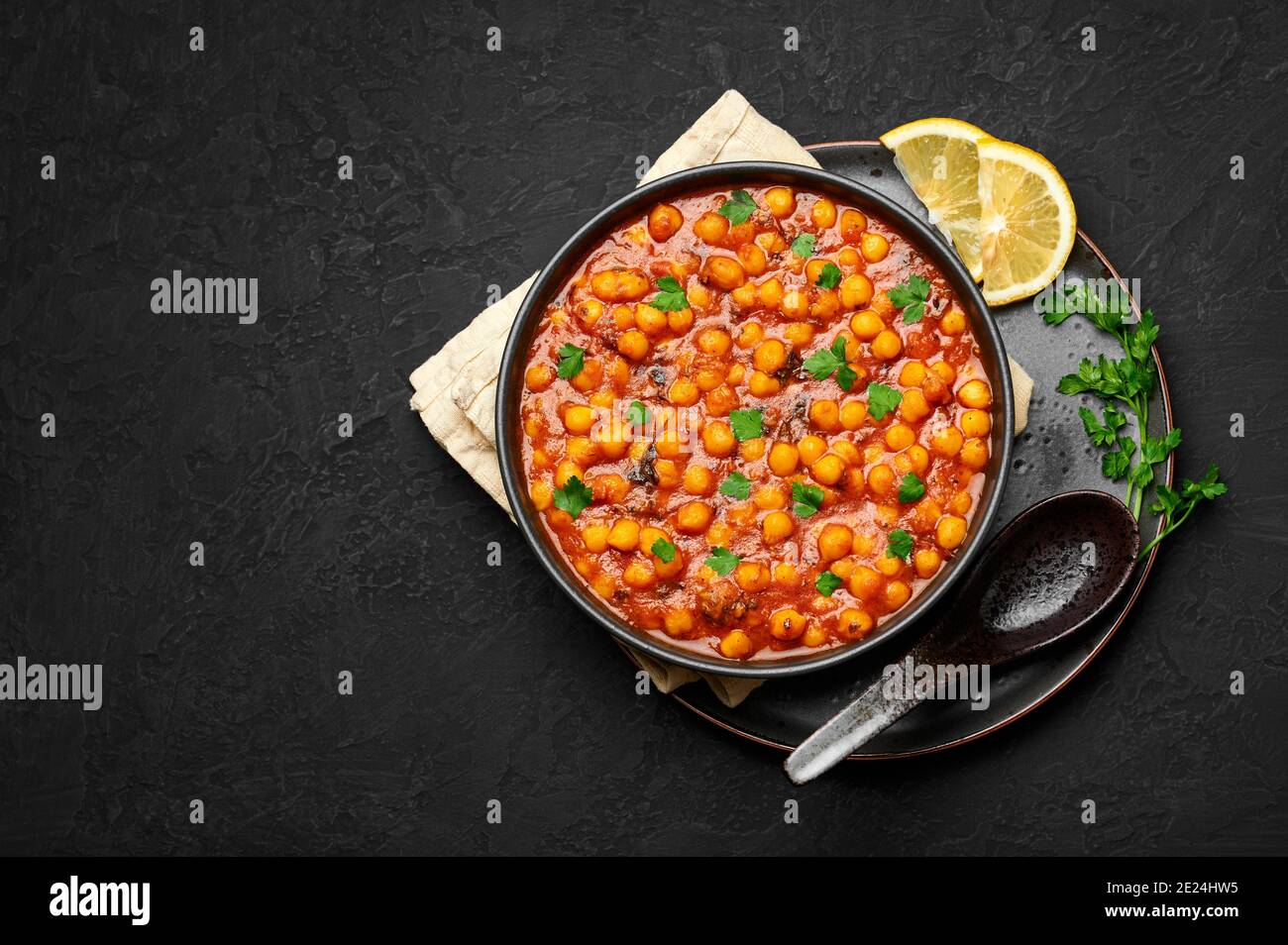 Chana Masala ou Chole dans un bol noir sur table en ardoise sombre. Cuisine indienne, légumes, pois chiches, plat de curry. Plats et repas végétariens épicés asiatiques. Copier l'espace Banque D'Images