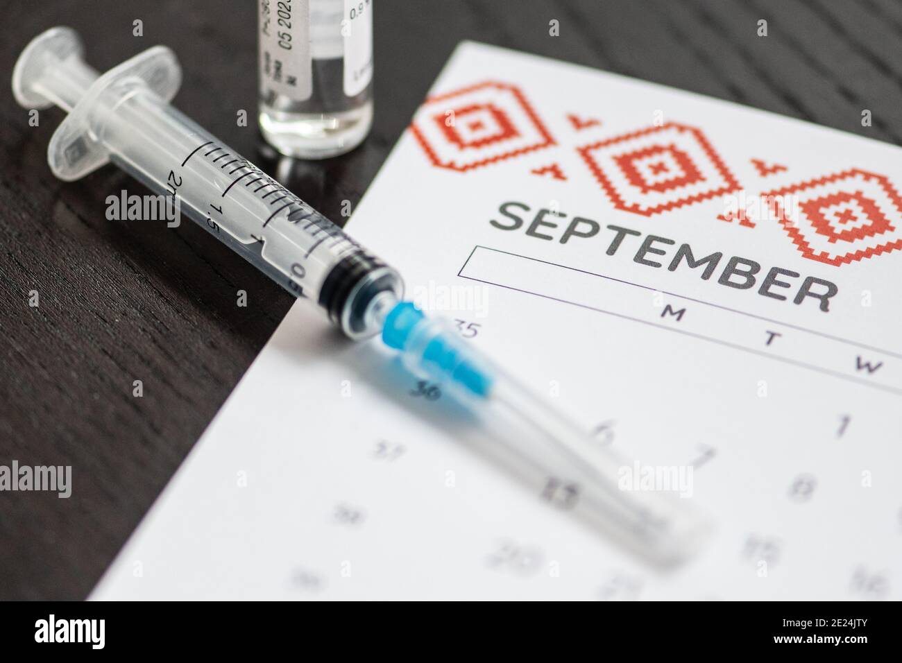 Seringue, flacon et calendrier avec mois de septembre sur une table noire prête à être utilisée. Antécédents de vaccin Covid ou coronavirus Banque D'Images