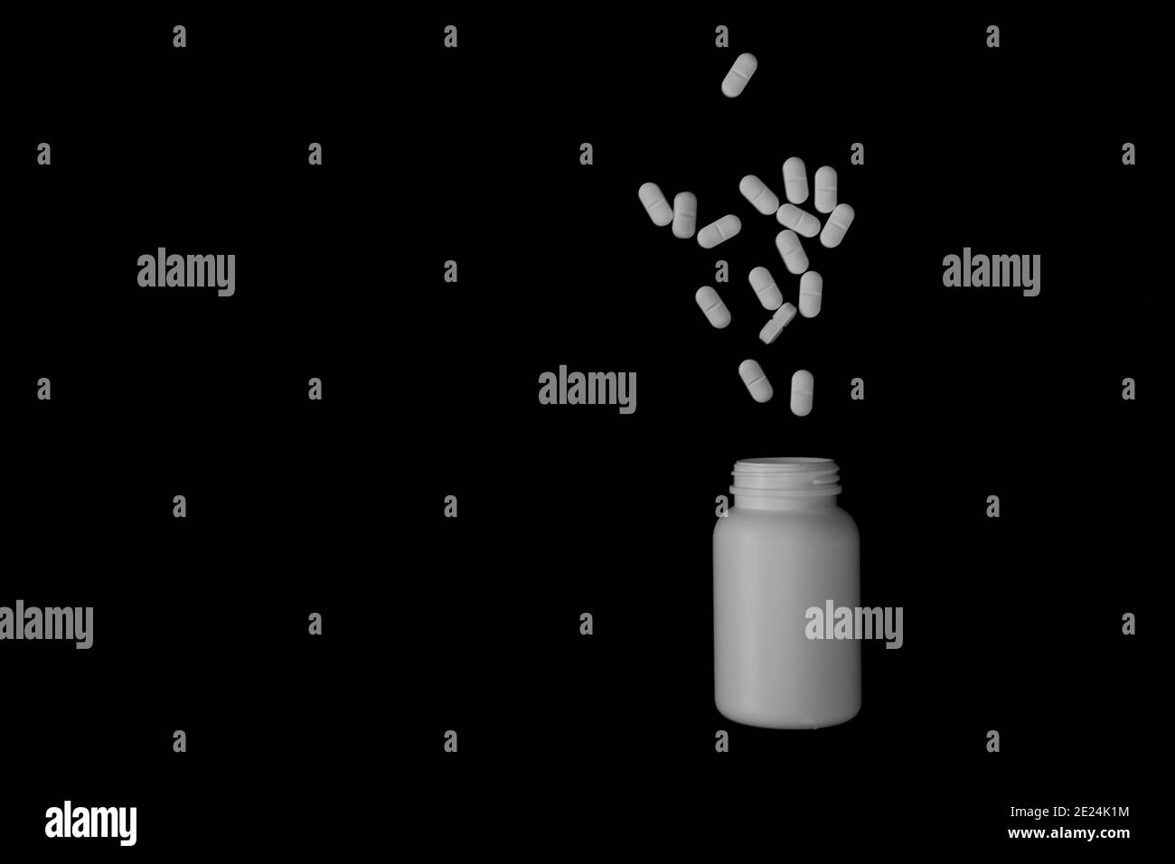 Dose isolée de comprimés de médicaments et leur flacon dans un arrière-plan noir Banque D'Images