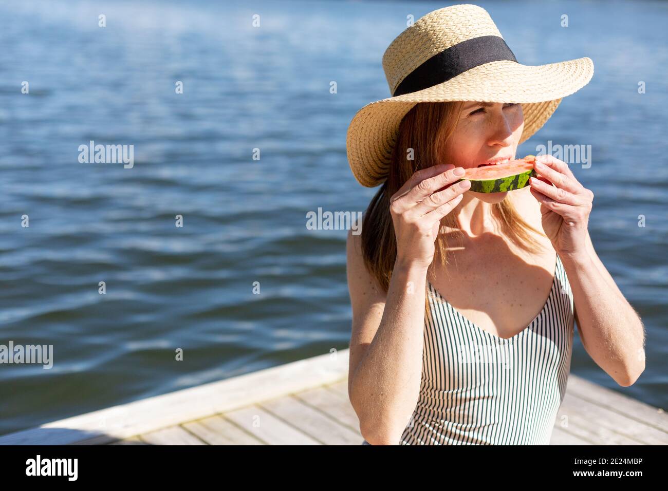 Femme sur la jetée en train de manger de la pastèque Banque D'Images