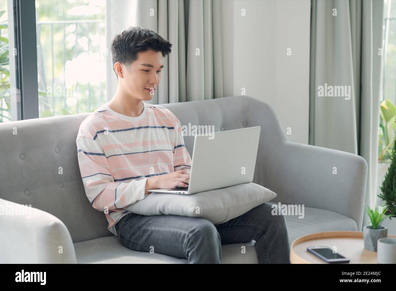Jeune homme se détendre sur le canapé avec un ordinateur portable Banque D'Images