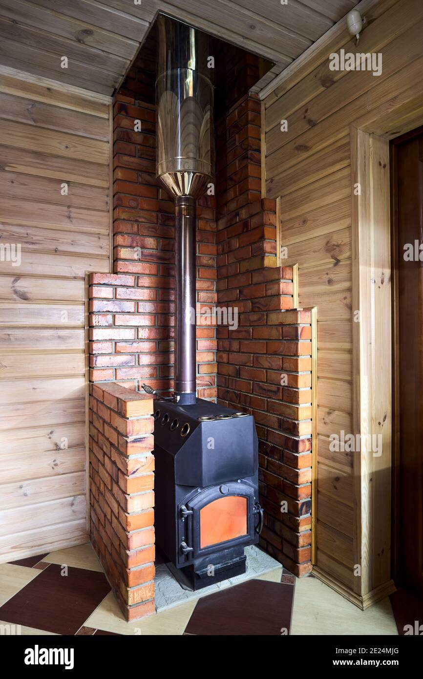 Élément intérieur de maison rurale. Poêle à bois en fonte d'acier brûlant  chaud sur carrelage à l'intérieur de la cheminée en brique, avec détecteur  de fumée de monoxyde de carbone Photo Stock -