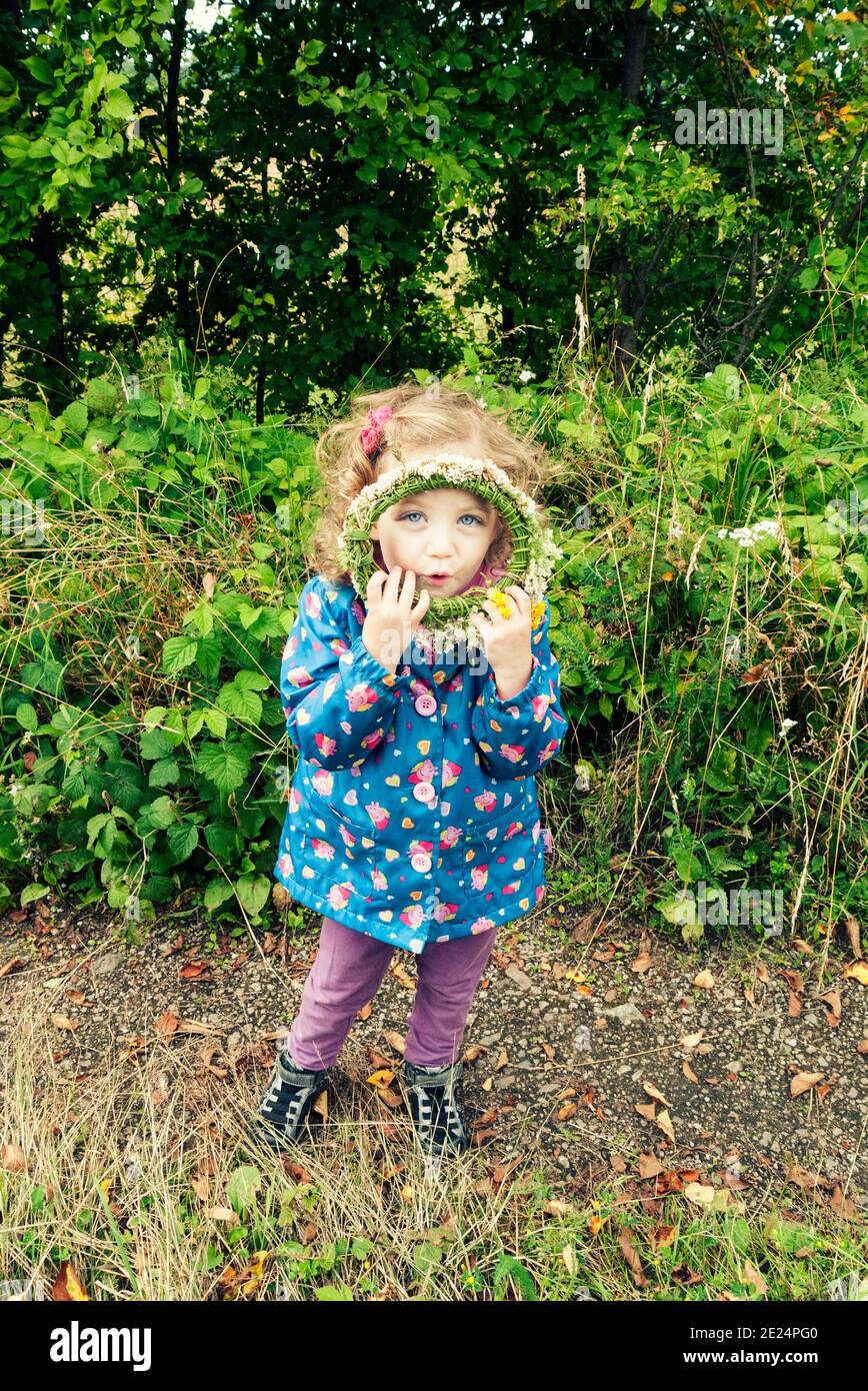 Portrait d'une fille debout à l'extérieur tenant une couronne devant son visage, en Pologne Banque D'Images
